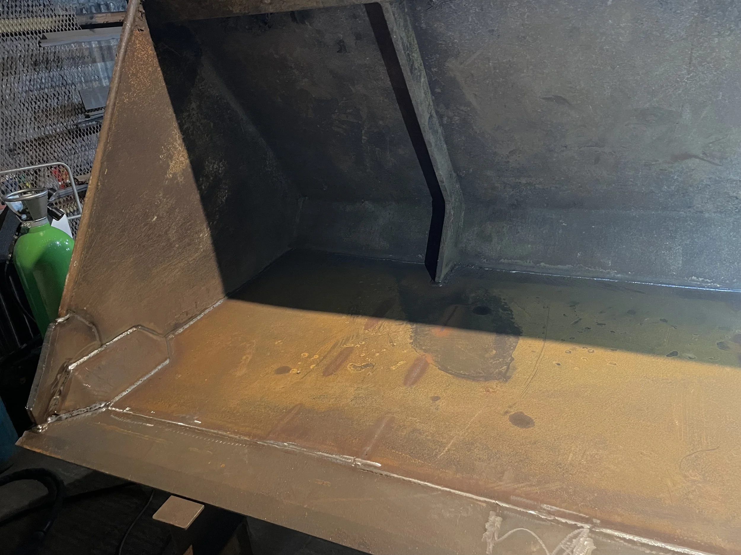 Interior of a large tele handler bucket, possibly part of construction or industrial machinery, with visible welds