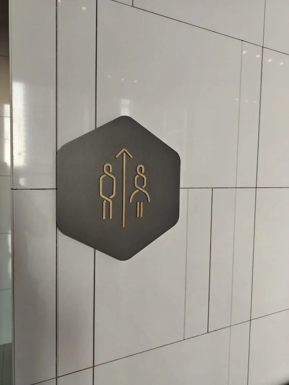 Sign indicating men's and women's restrooms with a directional arrow pointing upward.