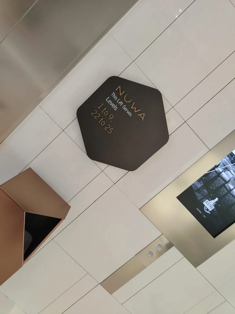An elevator floor indicator sign on the wall displaying 'Nuwa' and elevator level information from 1 to 25.