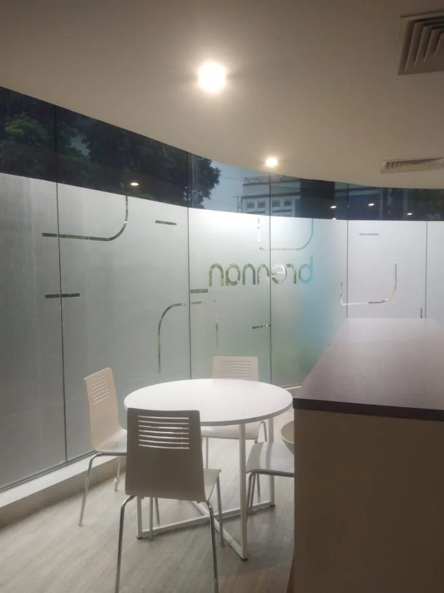 Empty office space with a round white table and four chairs near frosted glass walls.