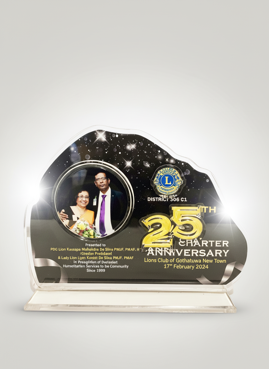 A commemorative plaque celebrating the 25th anniversary of the Lions Club of Gothatuwa New Town, dated February 17, 2024, with a photo of two people, a man in a black suit and a woman in glasses holding a bouquet, set against a black background with 