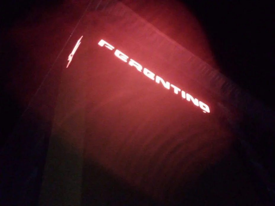 A red illuminated sign on a building with the word 'FERRIGTNG'.