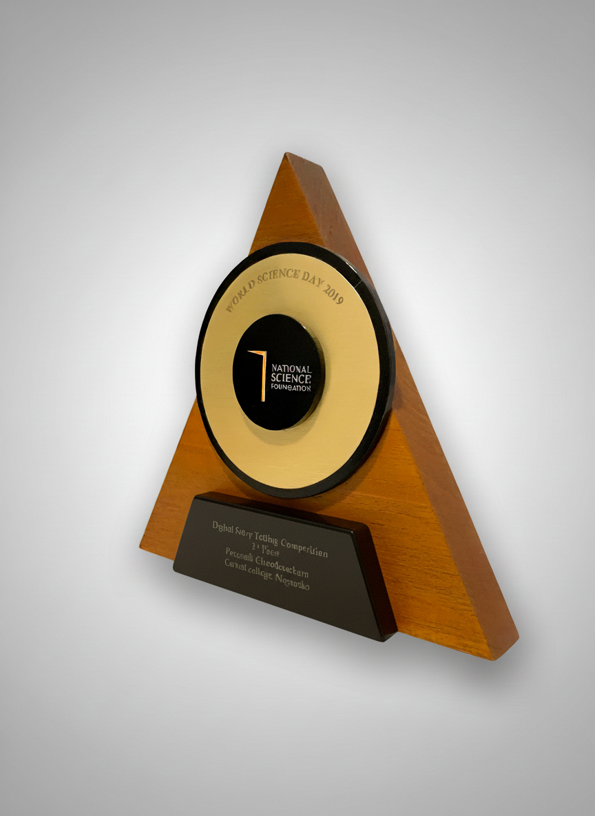 Triangular wooden award with a circular black and gold emblem for National Science Foundation, commemorating World Science Day 2019, with a plaque at the bottom listing recipients.