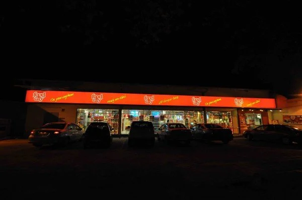 A Food City grocery store at night with a bright red sign and illuminated windows, and several parked cars in front.