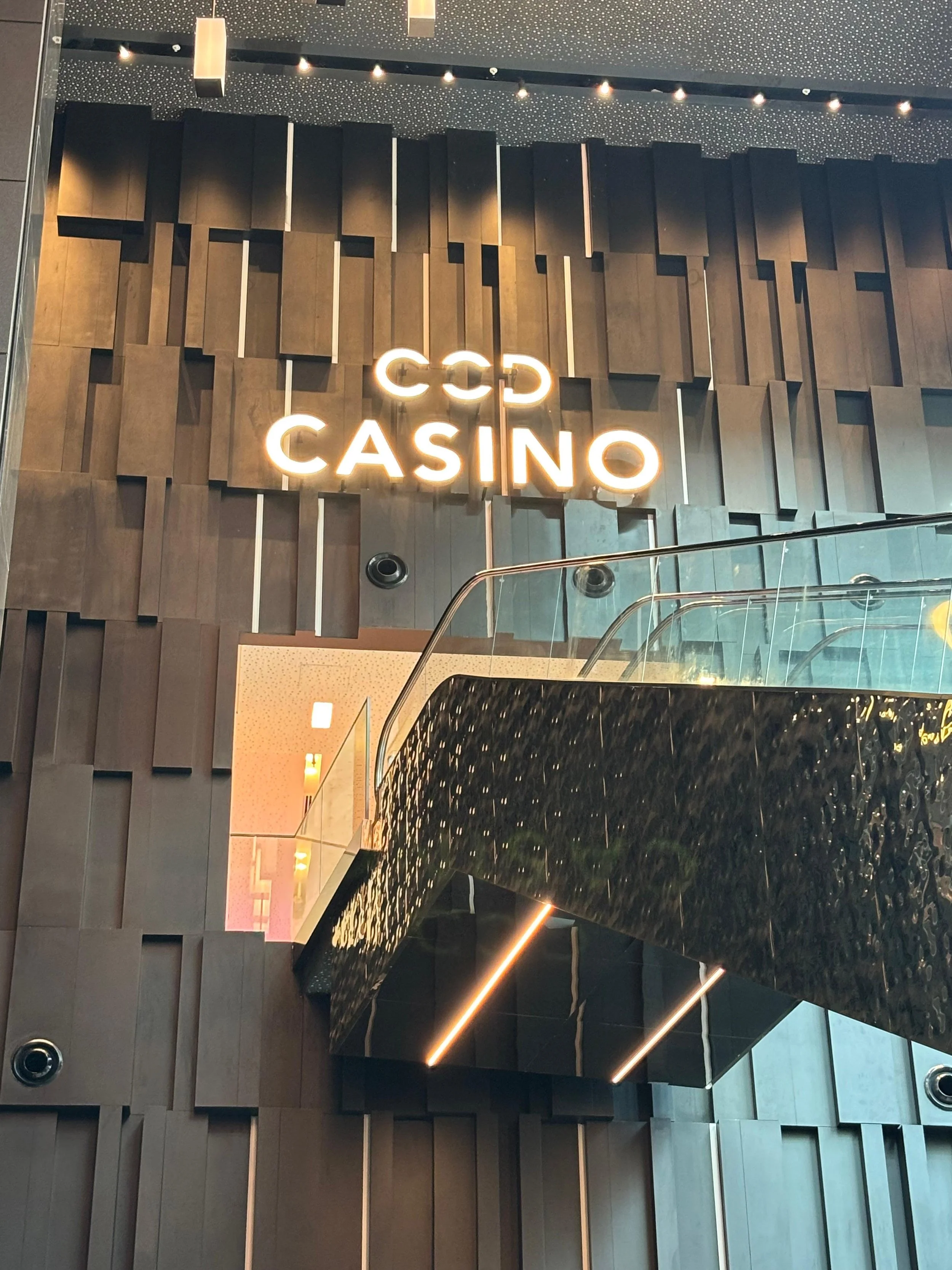 Interior shot of a casino entrance with a modern, artistic wall design and illuminated 'CASINO' sign.