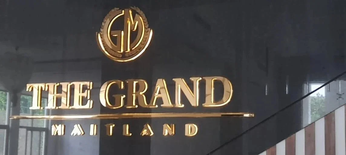 Sign for The Grand Maitland with a gold logo of intertwined letters