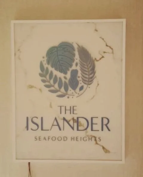 Sign for The Islander Seafood Heights with a logo featuring leaves and plant elements.