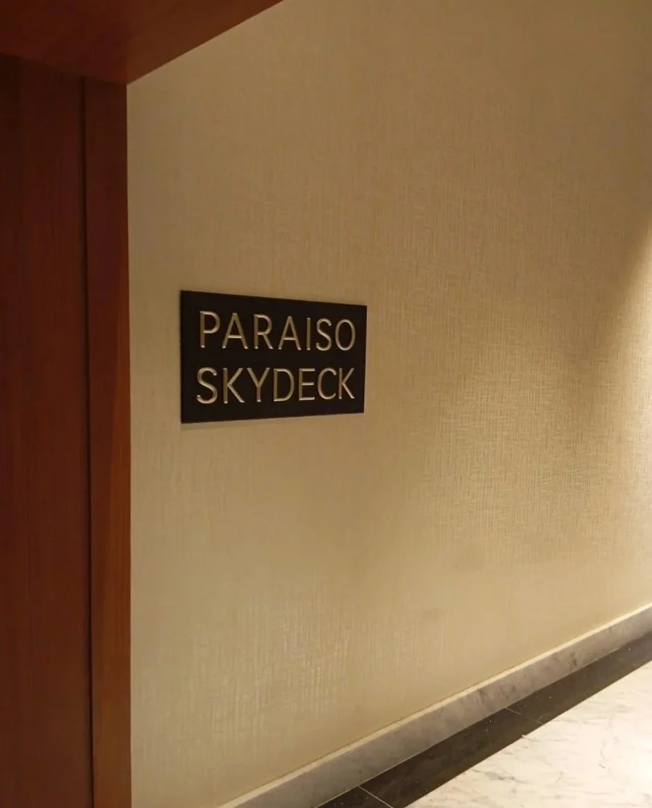 A hotel corridor wall with a sign that reads 'PARAISO SKYECK' in silver lettering on a black background.