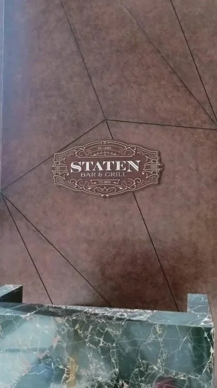 Floor with a sign for Staten Bar & Grill, and a countertop with green marble.