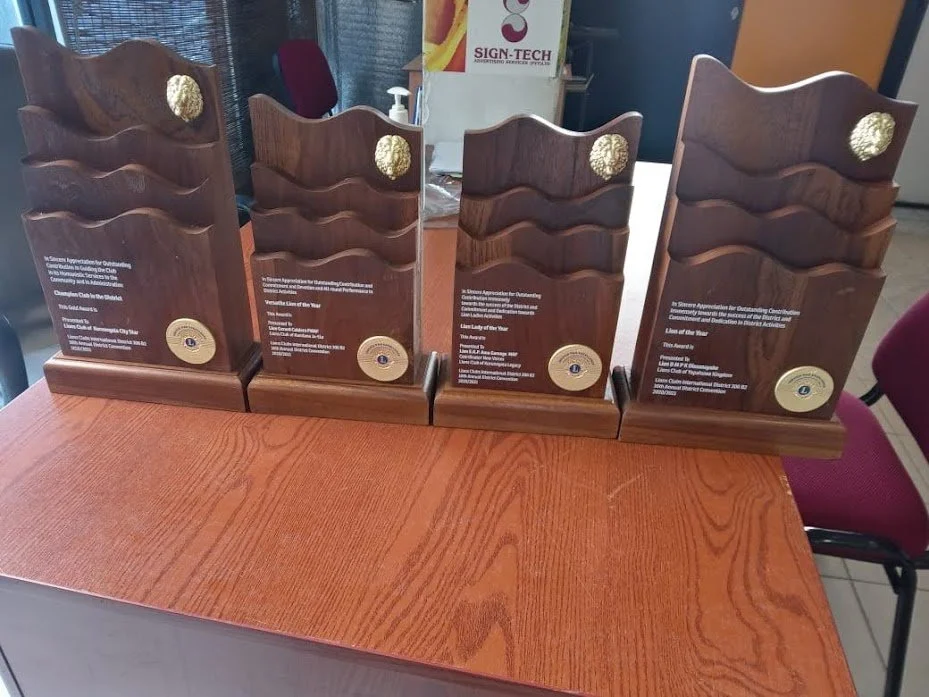 Four wooden awards or plaques with gold medallions on a table.