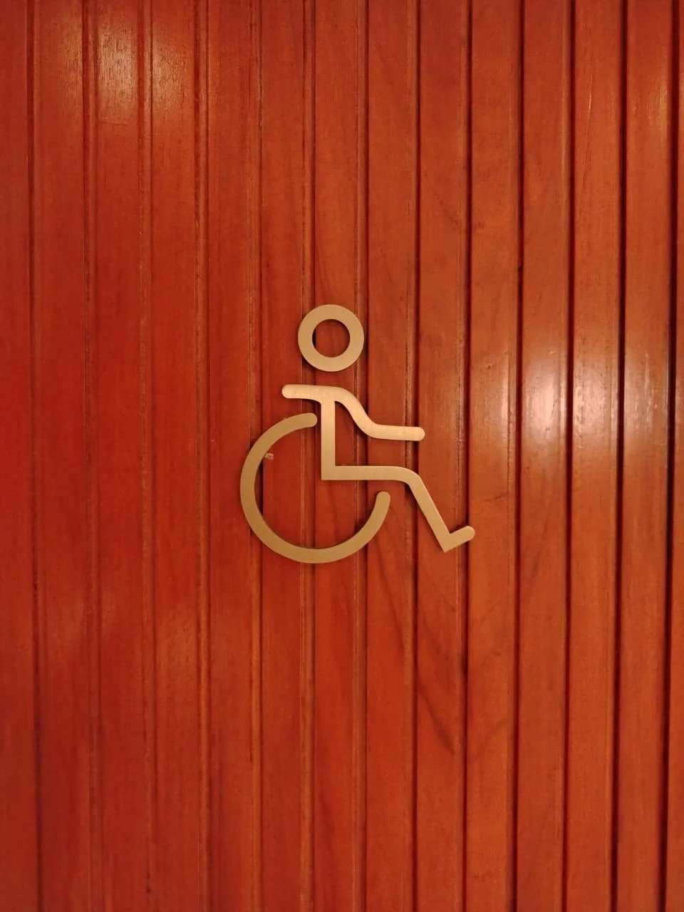 Handicap accessibility sign on wooden wall.