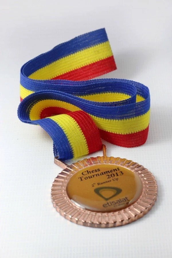 Medal with a rainbow-colored ribbon in blue, yellow, and red stripes, awarded for second runner-up in a 2013 chess tournament organized by Etisalat.