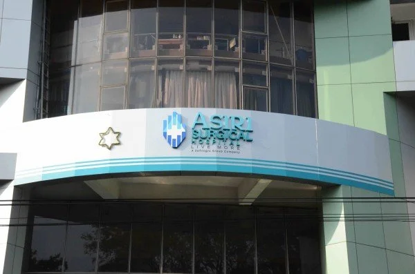Exterior of a modern building with a sign for ASIRI Super Cat Supermarket, featuring a logo with a blue hand and star symbol.