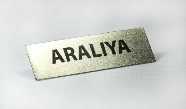 Metal nameplate with the name 'ARALIYA' in black letters.