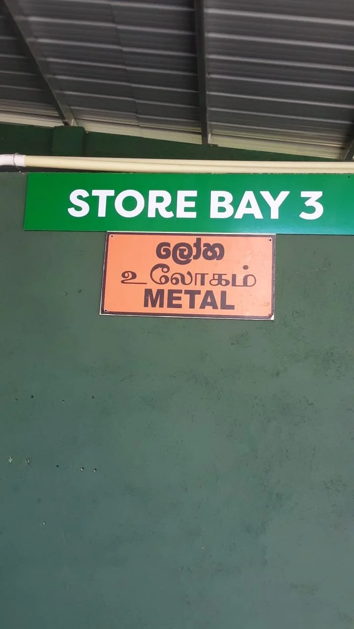 Sign pointing to Store Bay 3, with additional sign indicating metal section in Tamil and English.