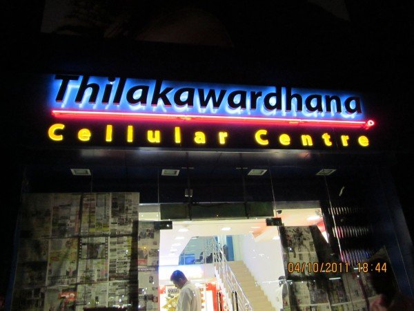 Signboard for Thilakawardhana Cellular Centre with illuminated blue, red, and yellow neon lights