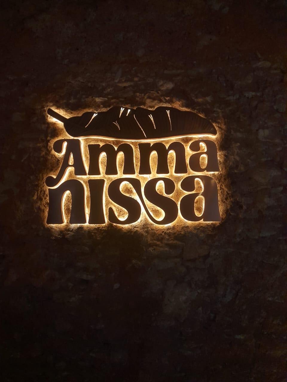 Backlit sign with a feather and the text "Amma Nissa" written in bold, stylized font.