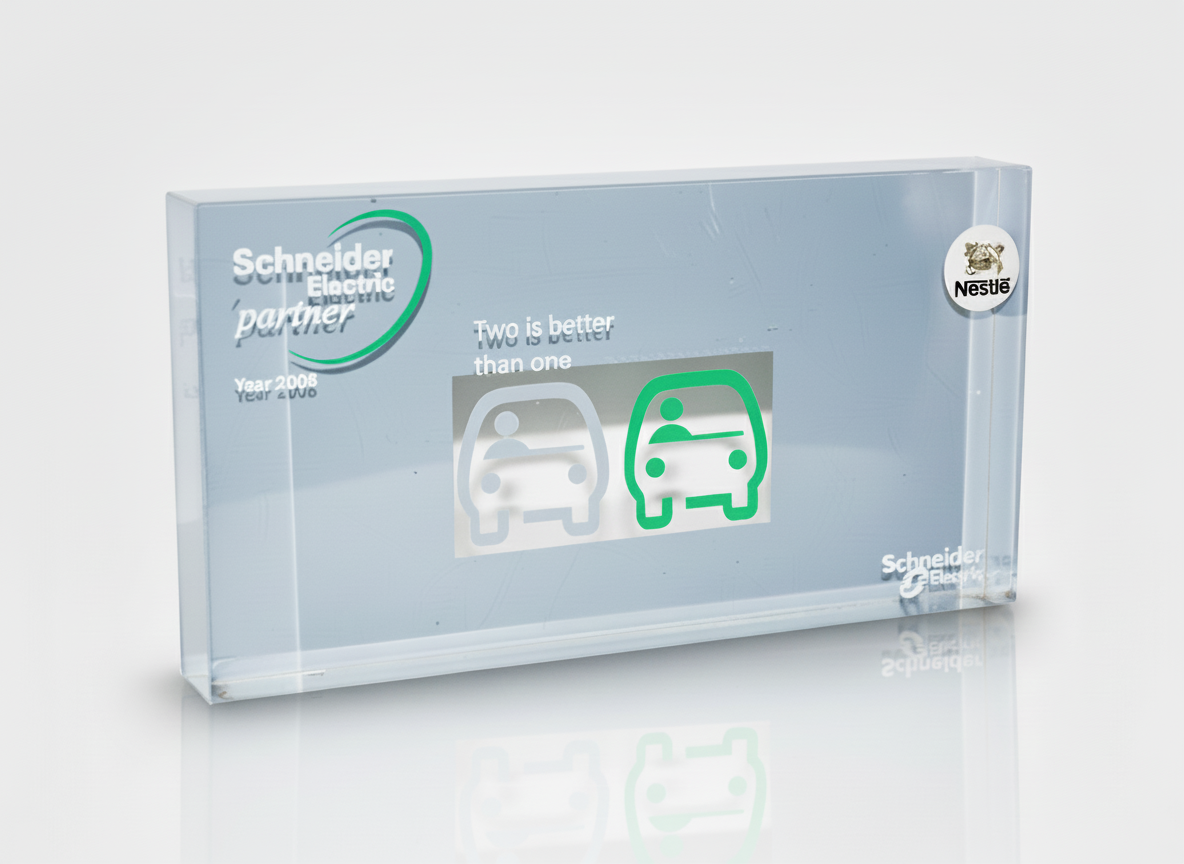 A clear glass plaque with the Schneider Electric and Nestlé logos, featuring a graphic comparing two cars with the text 'Two is better than one'.