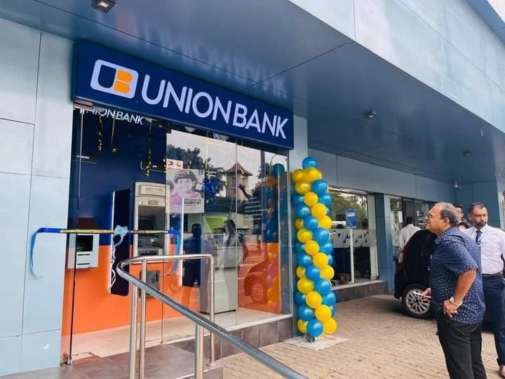 UnionBank branch entrance decorated with yellow and blue balloons, with people standing outside near the ATM and glass entrance door.