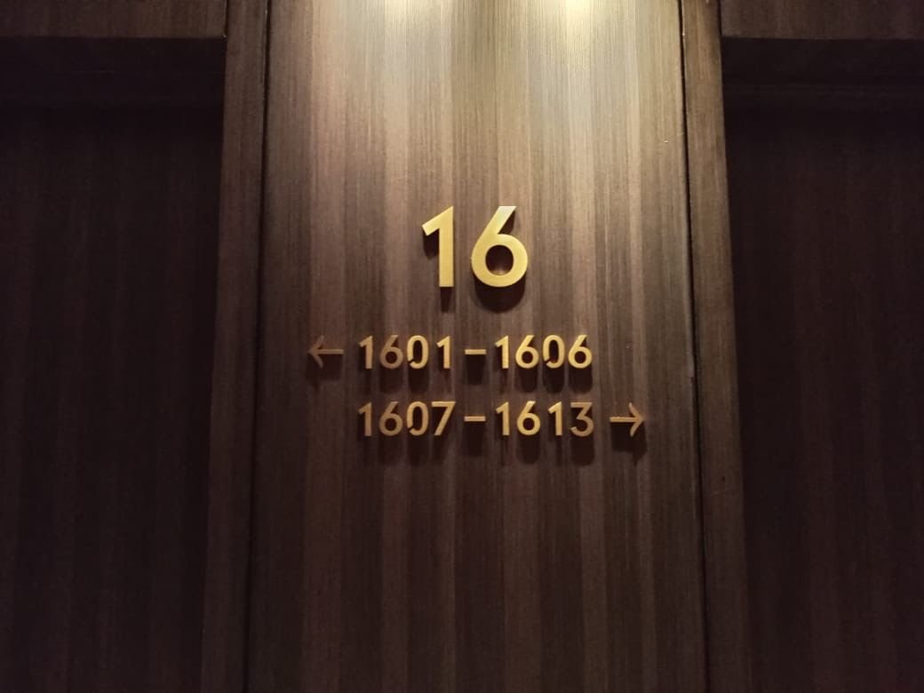 Room number 16 with directional signs for room ranges 1601-1606 to the left and 1607-1613 to the right, on a dark wooden wall.