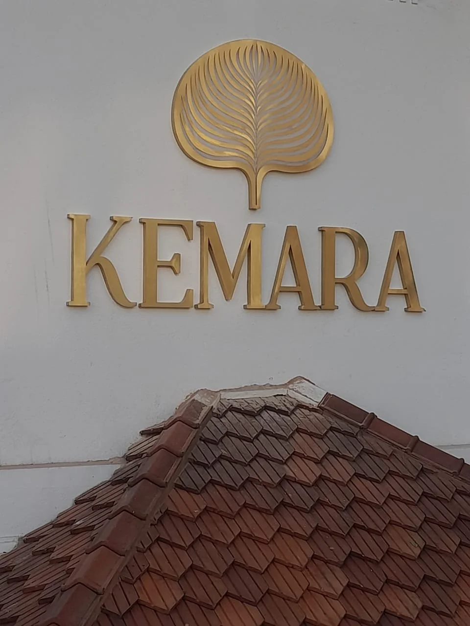 Sign with the logo and name 'Kemara' above a roof with reddish-brown clay tiles.