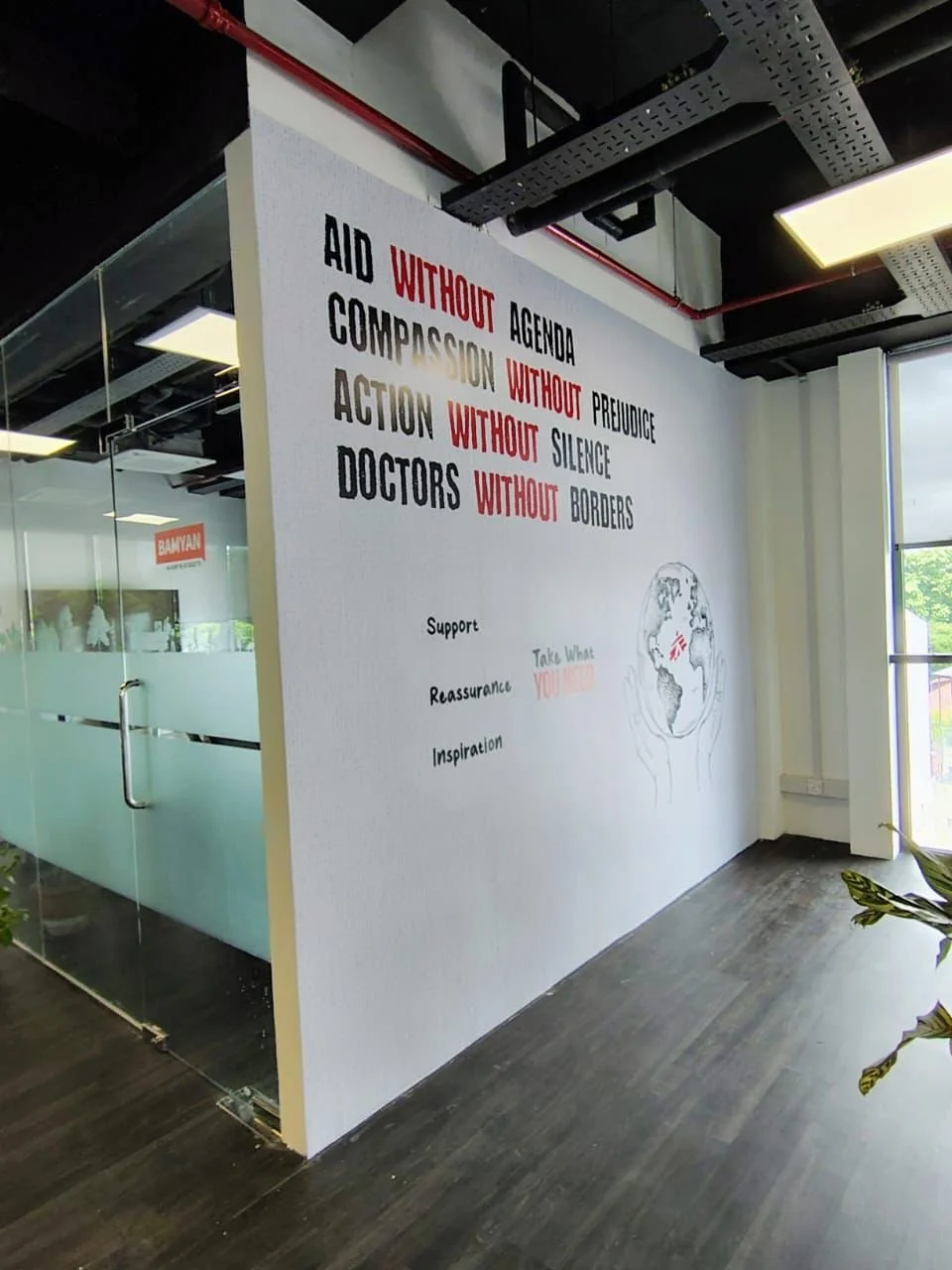 White wall with motivational quote about aid, compassion, action, and doctors, with words 'without' in red and supporting message, next to a simple line drawing of the Earth with a dove.