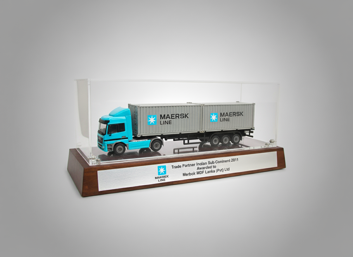 Model truck encased in glass display case with a wooden base, labeled as an award for a trade partnership with Maersk Line, awarded to Merbok MDF Lanka, from 2011.