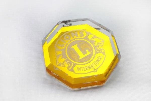 Octagonal Lions Club award or medallion with yellow logo and inscription on a white background