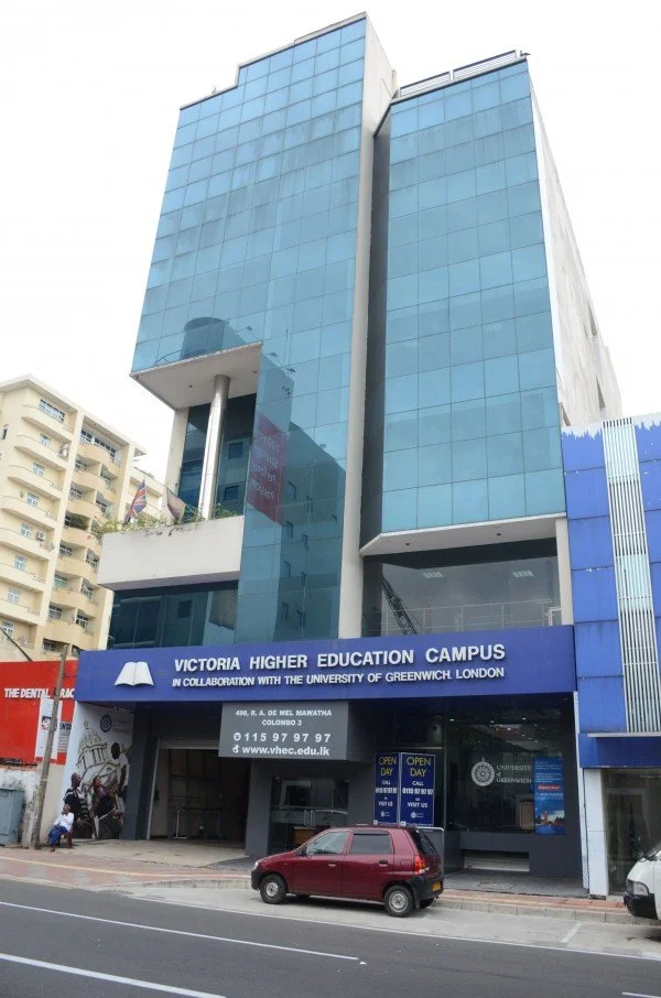 Modern high-rise building with blue glass exterior housing Victoria Higher Education Campus, in collaboration with the University of Greenwich London, located in Colombo, Sri Lanka.