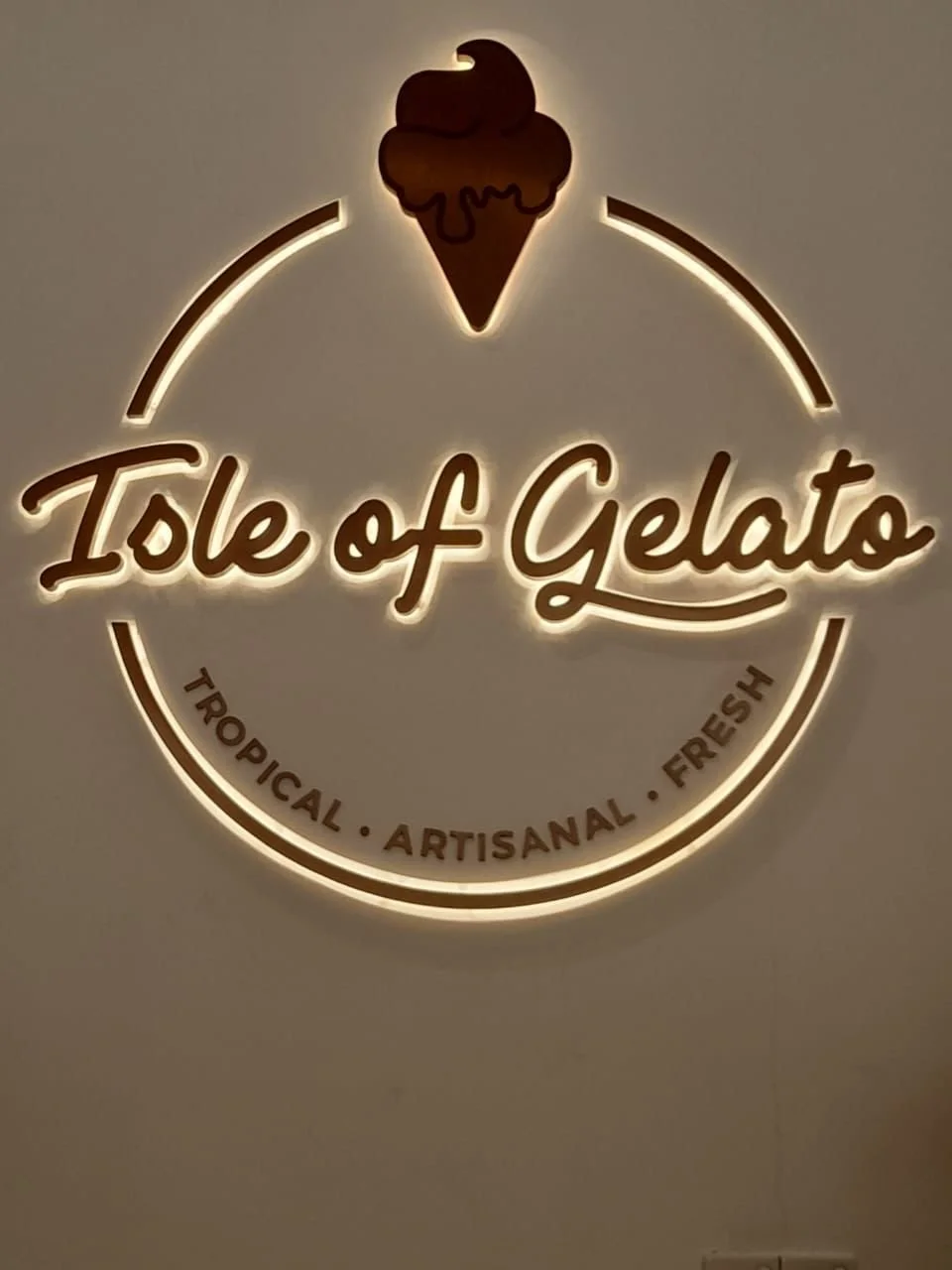 Neon sign for 'Island of Gelato' with a picture of an ice cream cone at the top, and the words 'Tropical, Artisanal, Fresh' at the bottom.