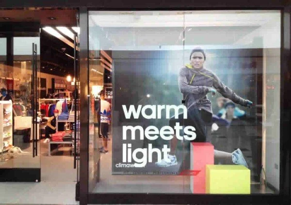 Store window display showcasing an advertisement with a woman in athletic clothing and the words "warm meets light".