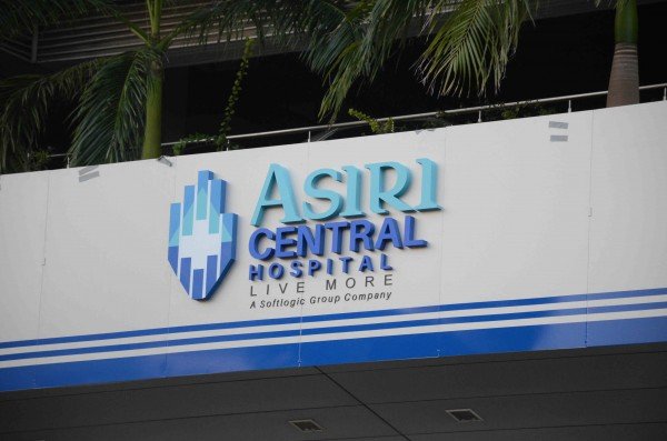 Sign for Asiri Central Hospital with palm trees in the background.