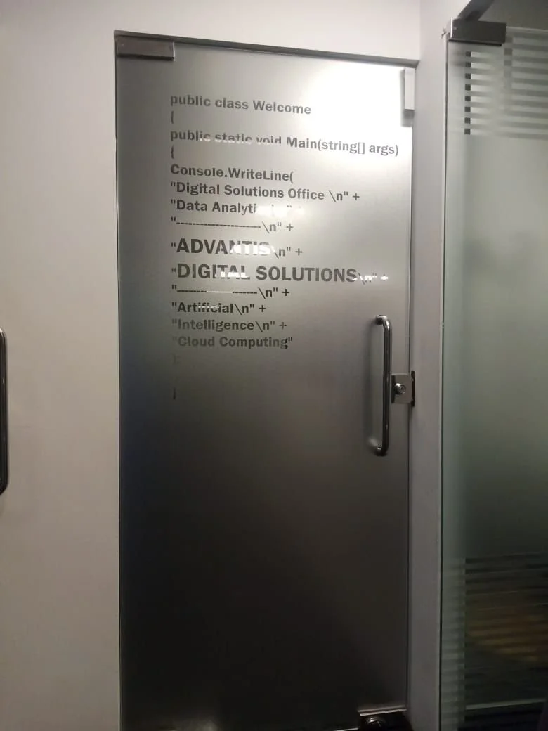A door with a metal surface has text resembling a computer code outline, mentioning a Digital Solutions Office and data analytics, artificial intelligence, and cloud computing.