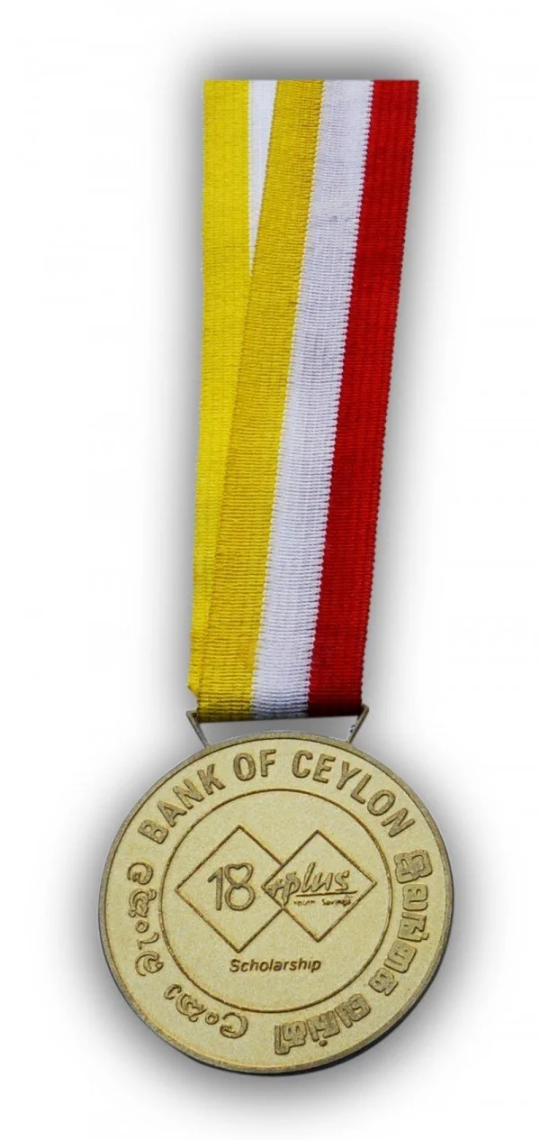 Gold-colored medal with a red, yellow, and white striped ribbon, engraved with 'Bank of Ceylon Scholarship' and the number 18, including logos and text in English and another language.