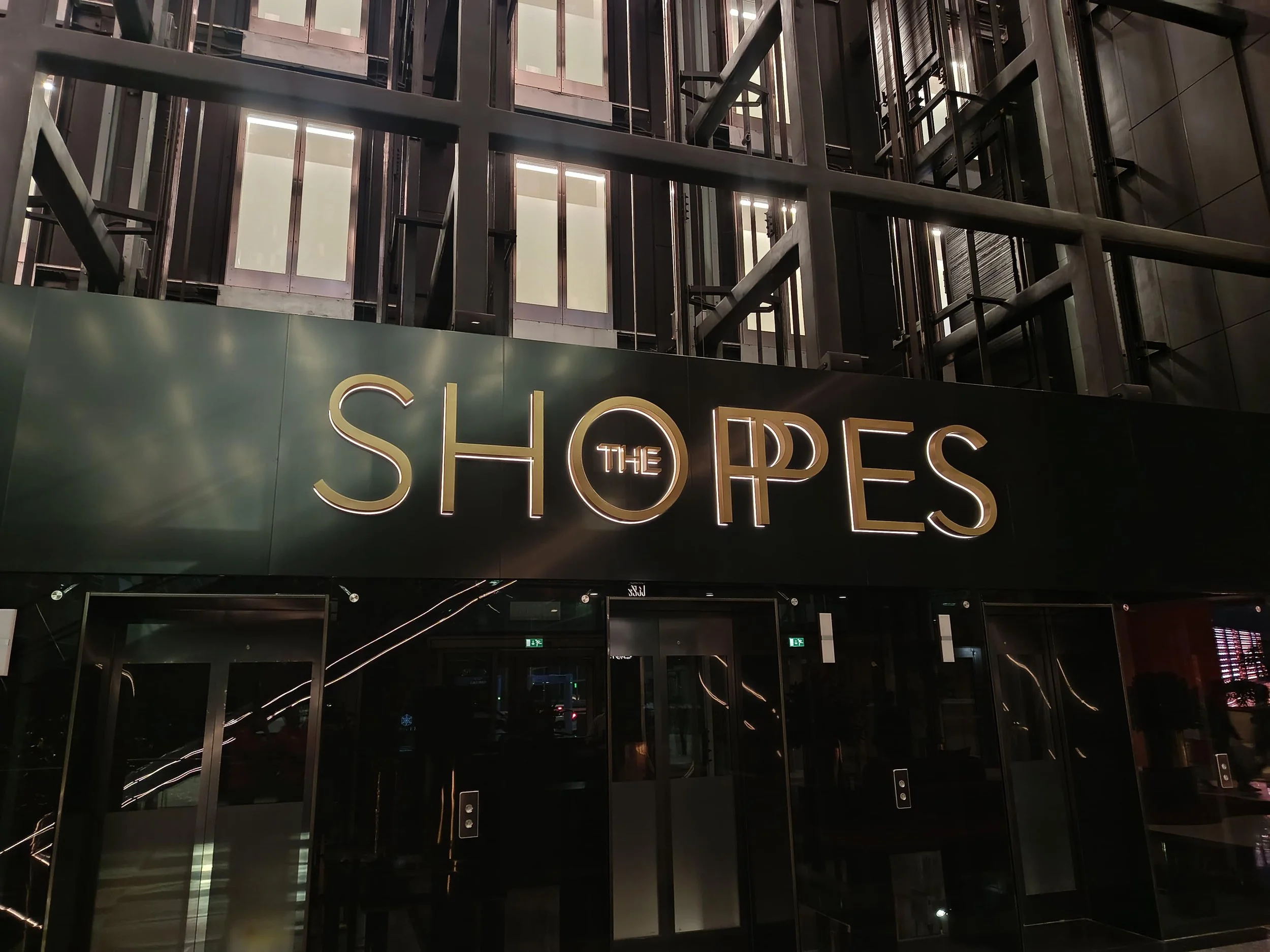 Exterior view of a modern building with a neon sign reading 'SHOP THE P'.