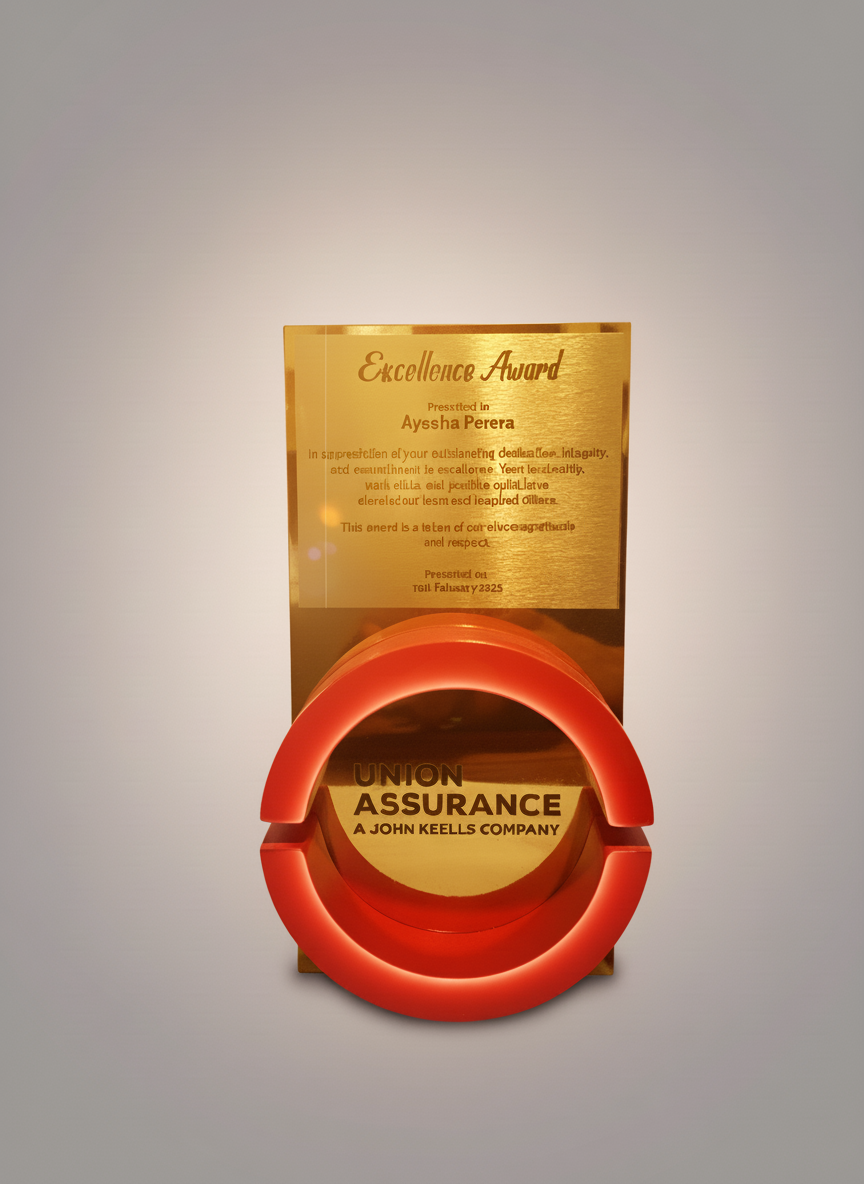 A gold-colored award plaque with a red circular emblem at the bottom, inscribed with "UNION INSURANCE A. JOHN KEELLS COMPANY." The plaque above is labeled "Excellence Award" and features faded text about the recipient, Ayssa Perera.