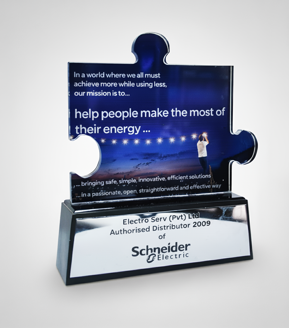 A glass trophy with a puzzle piece shape on top displaying a motivational message about energy and efficiency, with a metal base labeled as an authorized distributor of Schneider Electric.