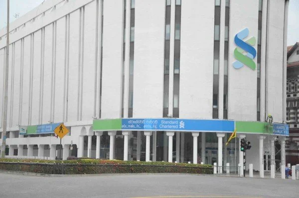 Exterior of a bank building with the Standard Chartered logo and banners.