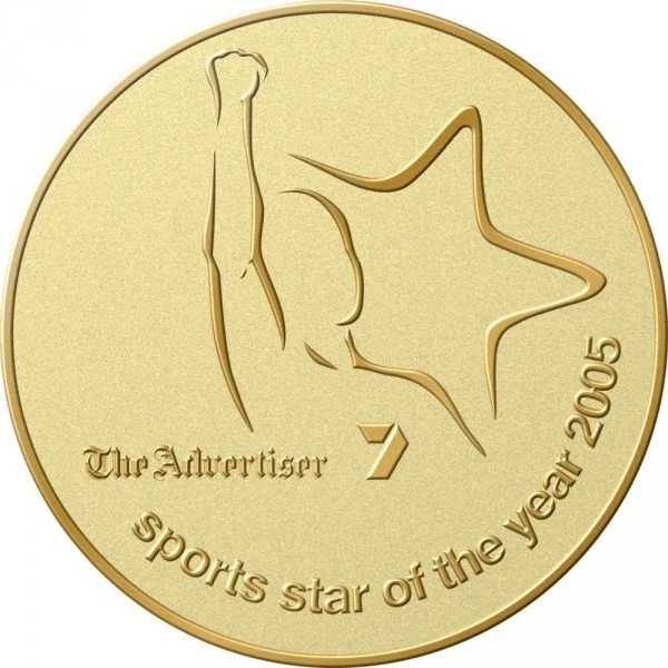 Gold-colored Australian sports star coin from 2005 featuring a stylized kangaroo and star with text 'The Advertiser 7 sports star of the year 2005'.