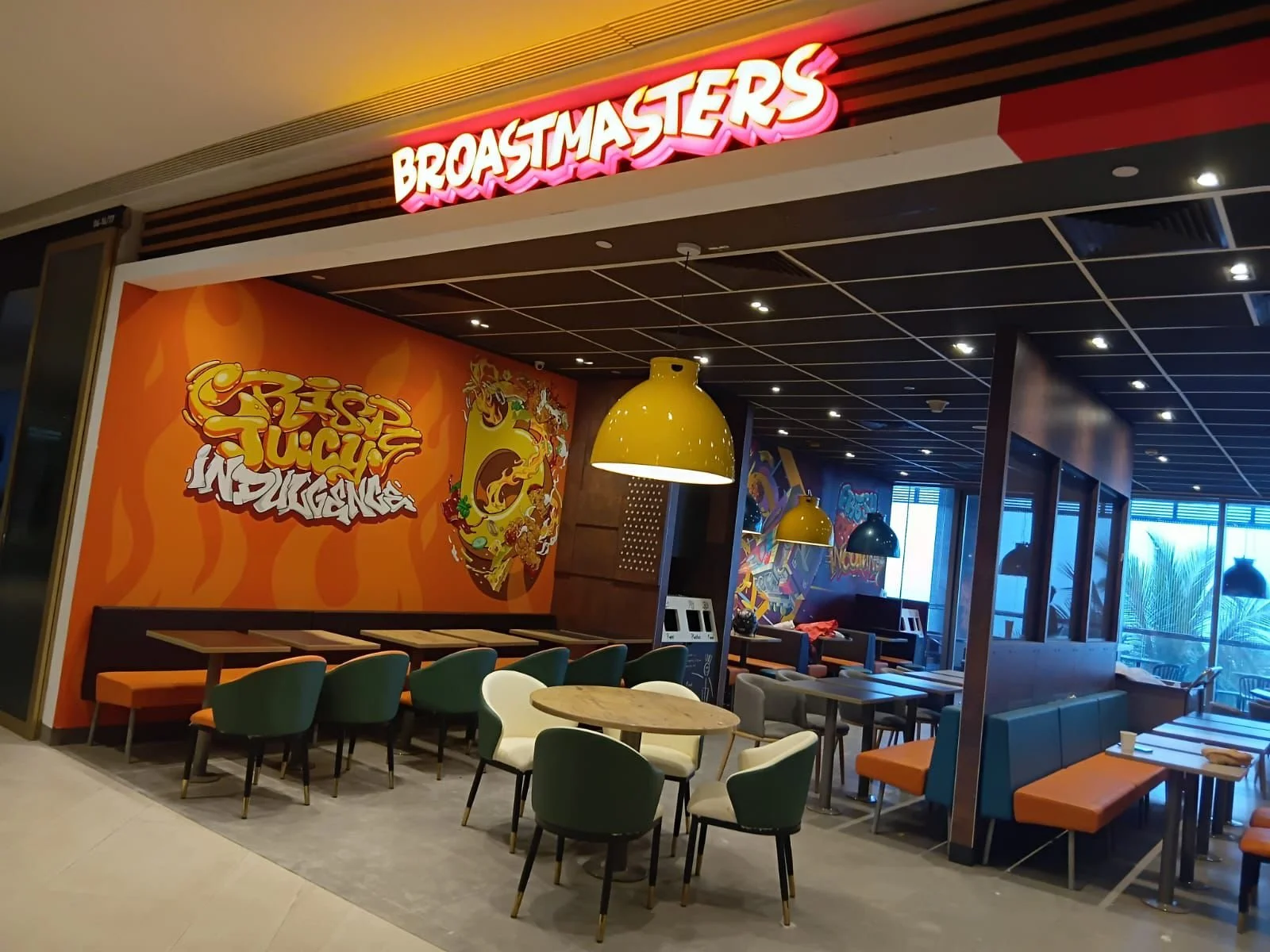 Interior of a restaurant called Broastmasters with colorful graffiti art and seating area with tables and chairs.