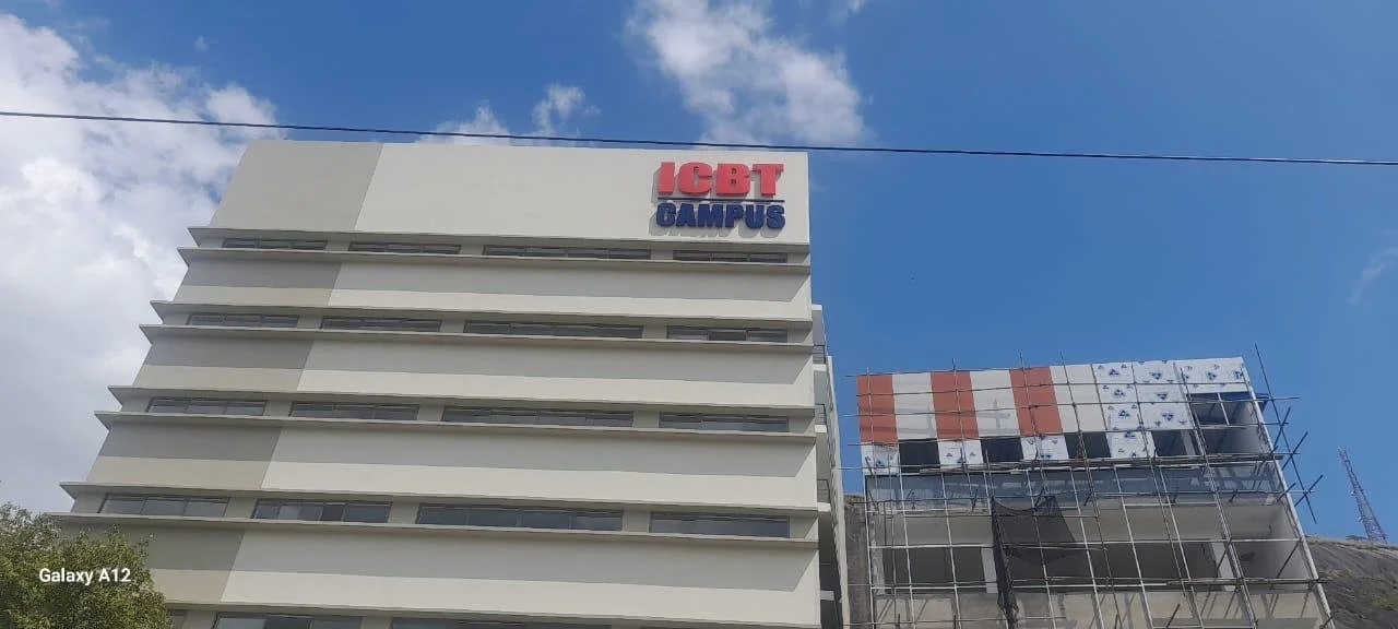 A multi-story building with the sign 'ICBT CAMPUS' on top, and the building under construction on the right with scaffolding and partial exterior panels.