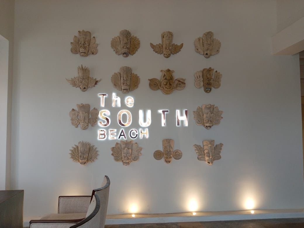 Wall art displaying the text 'The South Beach' with decorative wooden masks above and lighting below.