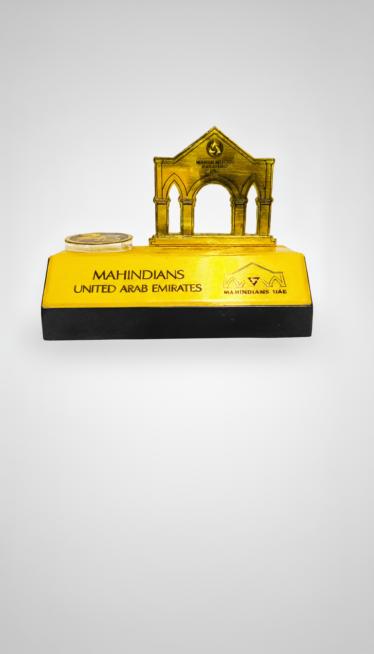Yellow and black stand with a small model of a building and a coin, labeled 'Mahindians United Arab Emirates'.
