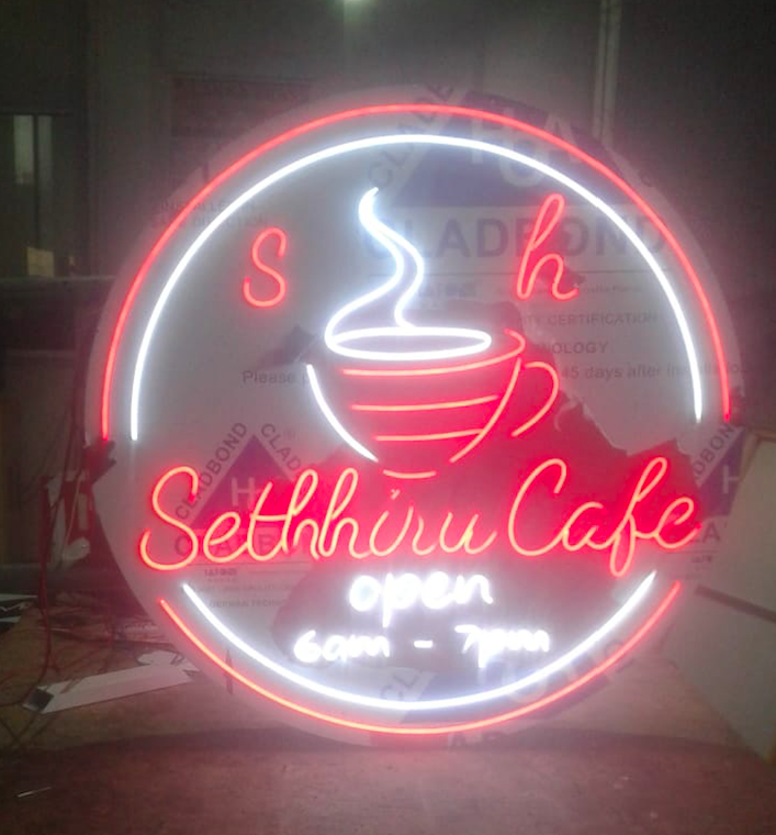 Neon sign for Setthiru Cafe featuring a steaming coffee cup, the cafe's name in cursive, and operating hours from 6 am to 7 pm.