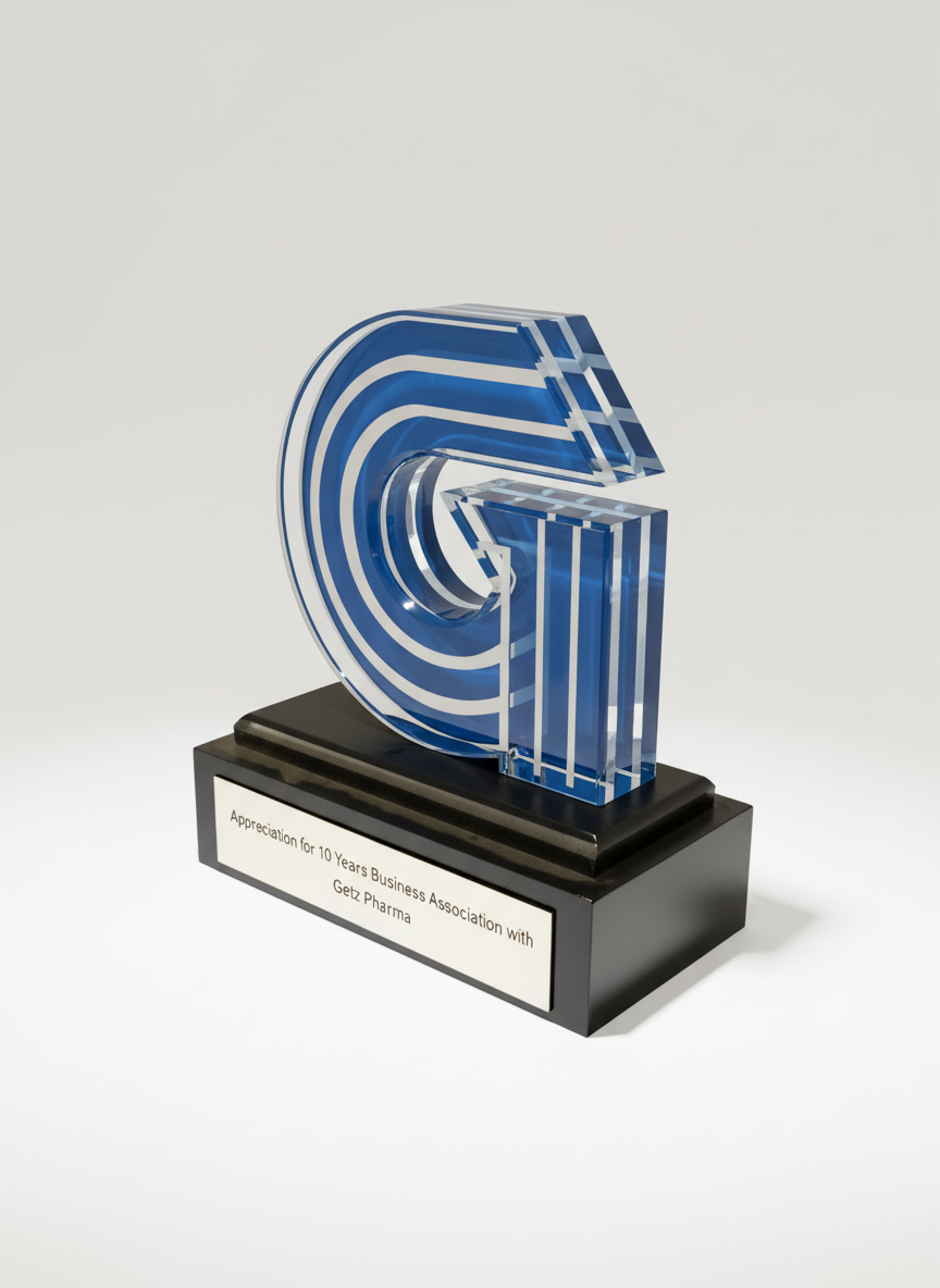 A glass award shaped like the letter G with blue and clear stripes on a black base, engraved with a message celebrating 10 years of a business association with Getz Pharma.