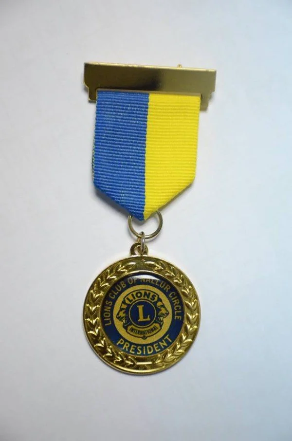 A Lions Club of Wallur Circle President medal with a yellow and blue ribbon.