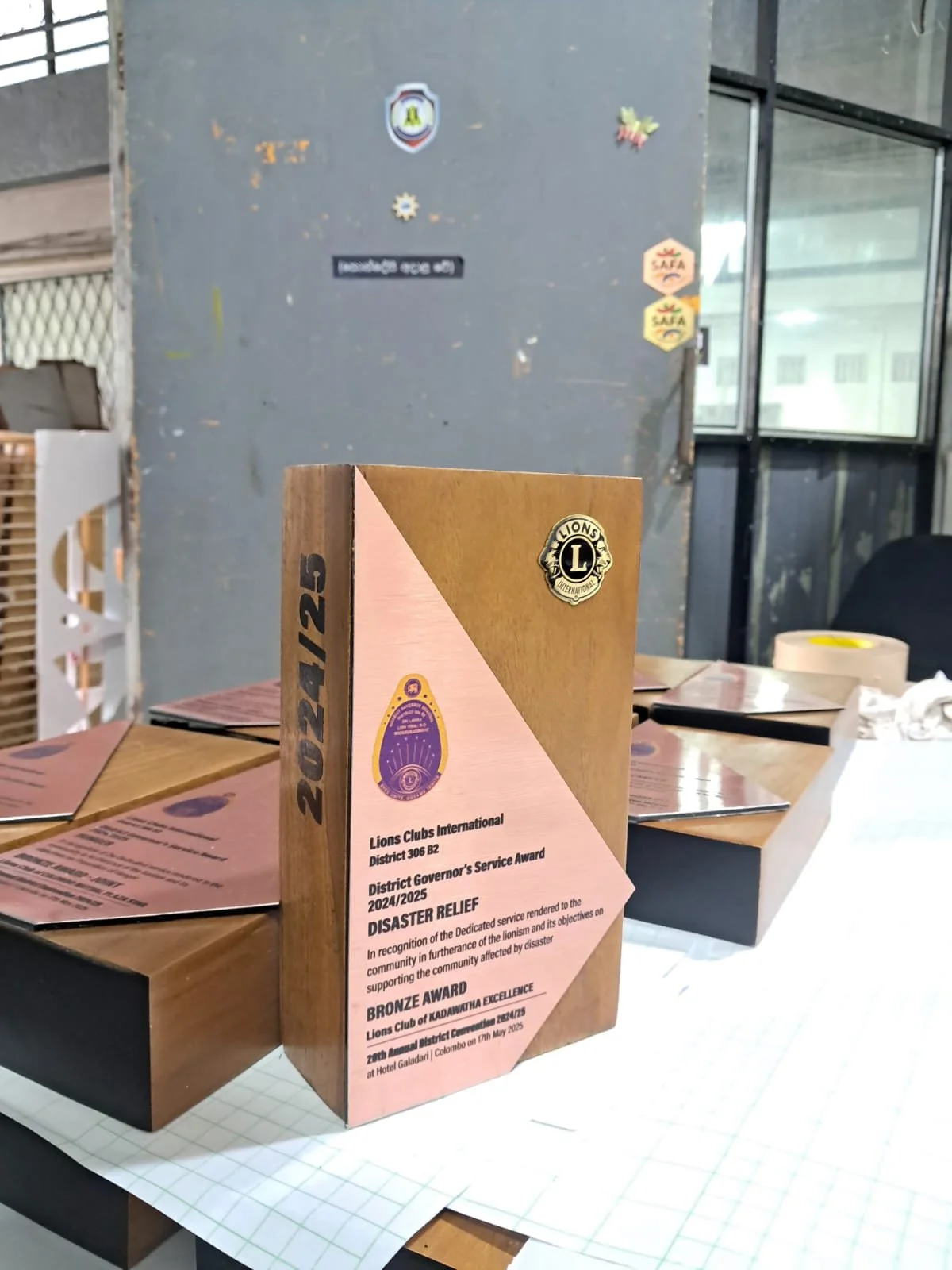Lions Clubs award certificate on a table during an event, with a gray wall and window in the background.