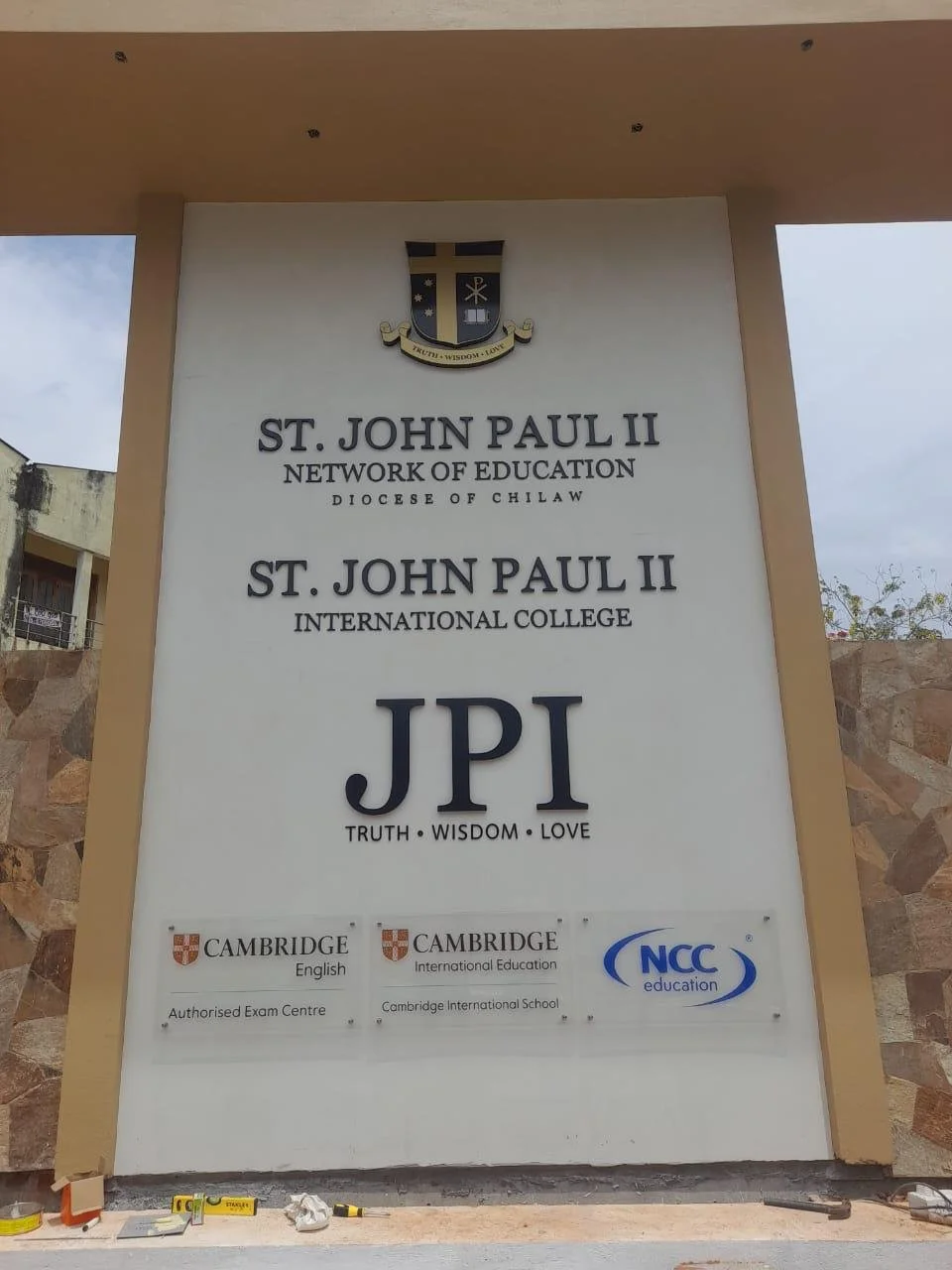 Sign for St. John Paul II Network of Education and International College in Chilaw, featuring logos for Cambridge English, Cambridge International Education, and NCC Education.