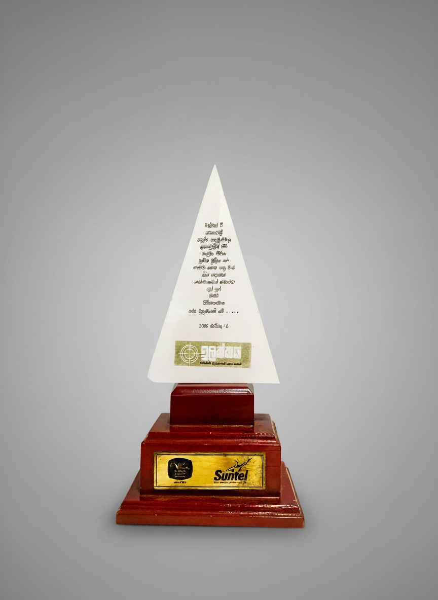 A trophy with a wooden base, a gold plaque, and a white triangular top with text in a non-English language and a logo.
