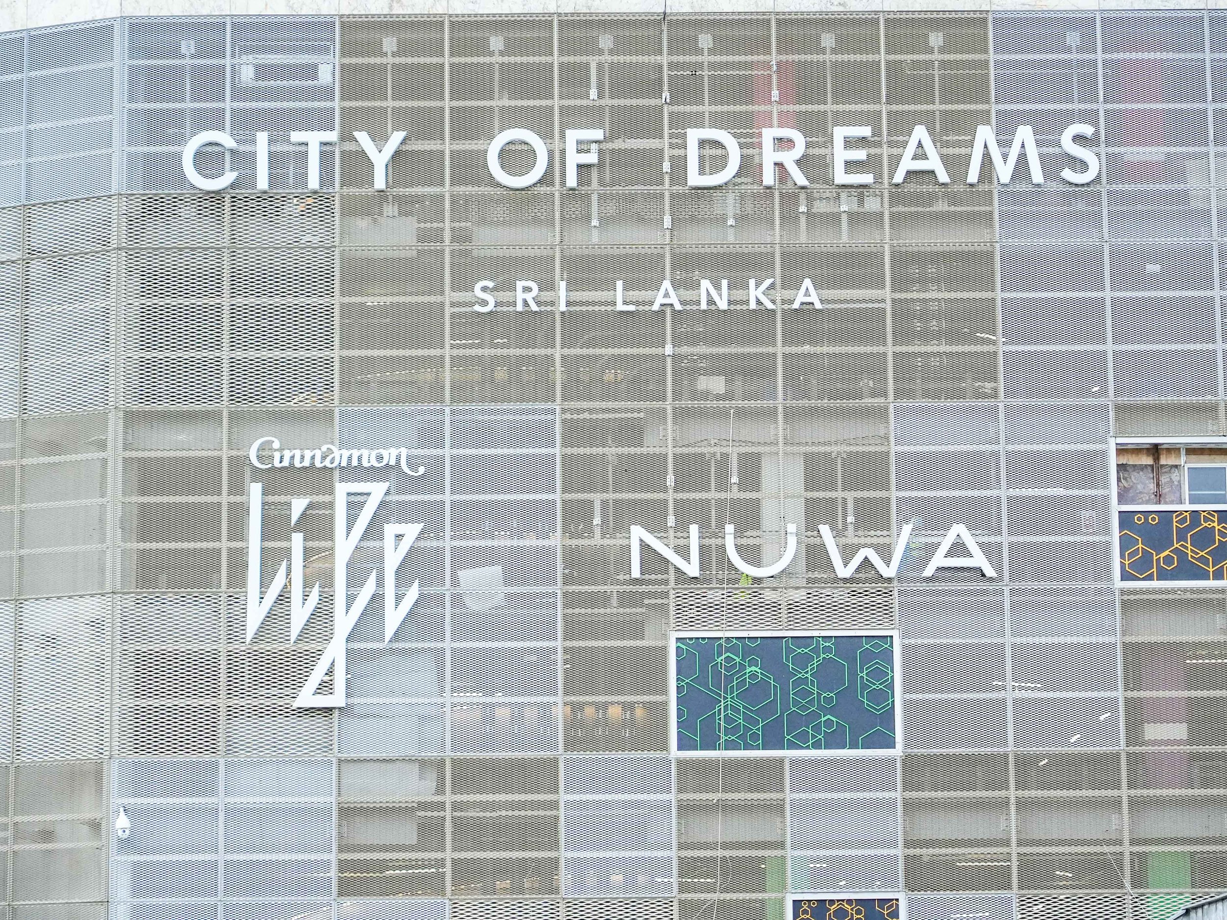 Modern building facade with large white letters spelling 'CITY OF DREAMS' and 'SRI LANKA', metal grid design, and decorative elements.